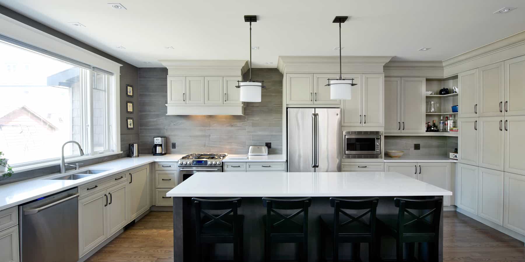 Open-concept two-tone kitchen with cream coloured upper cabinets, dark lower cabinets and spacious island.